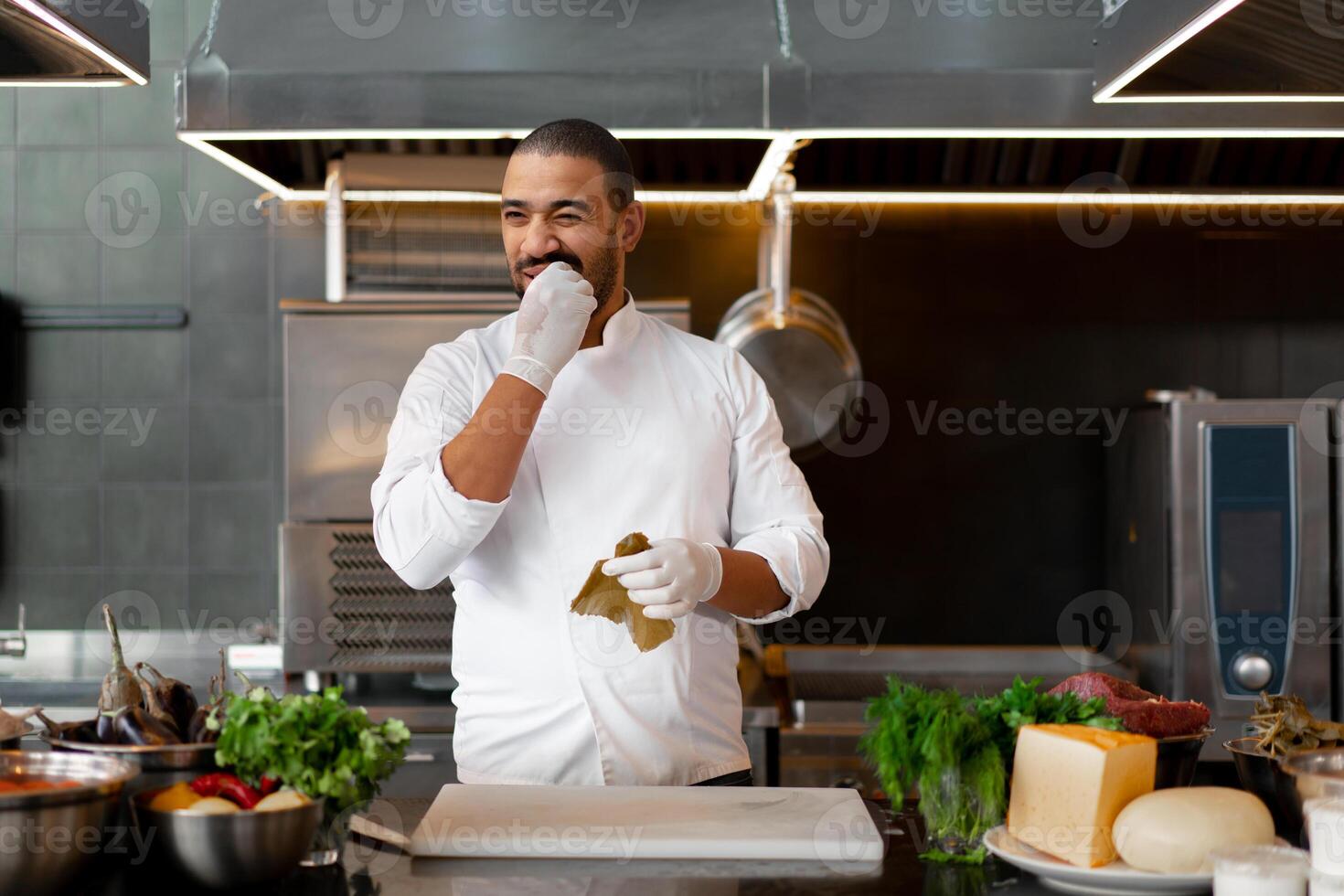 stilig ung afrikansk kock stående i professionell kök i restaurang framställning en måltid av kött och ost grönsaker. foto