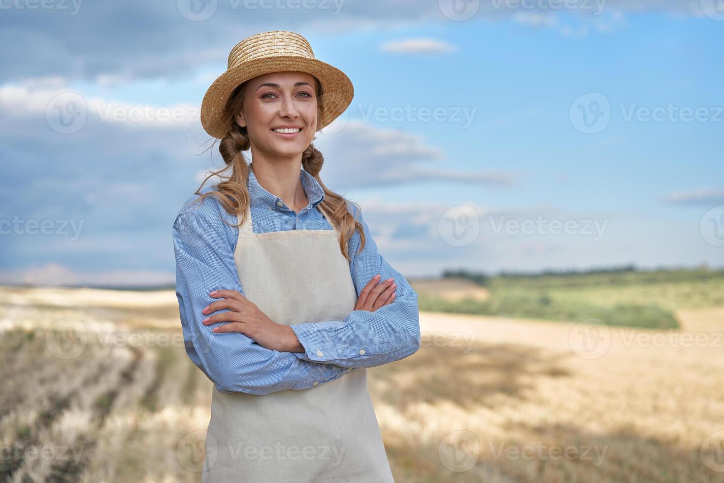 kvinna jordbrukare sugrör hatt förkläde stående jordbruksmark leende kvinna agronom specialist jordbruk jordbruksnäringen Lycklig positiv caucasian arbetstagare jordbruks fält foto