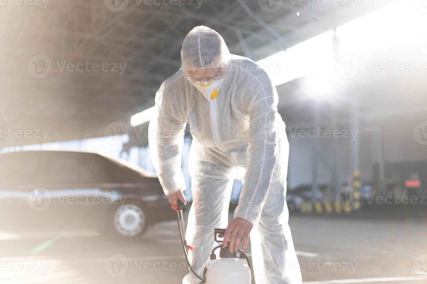 man klädd vit skyddande overall besprutning yta antibakteriell desinfektionsmedel spruta under karantän foto