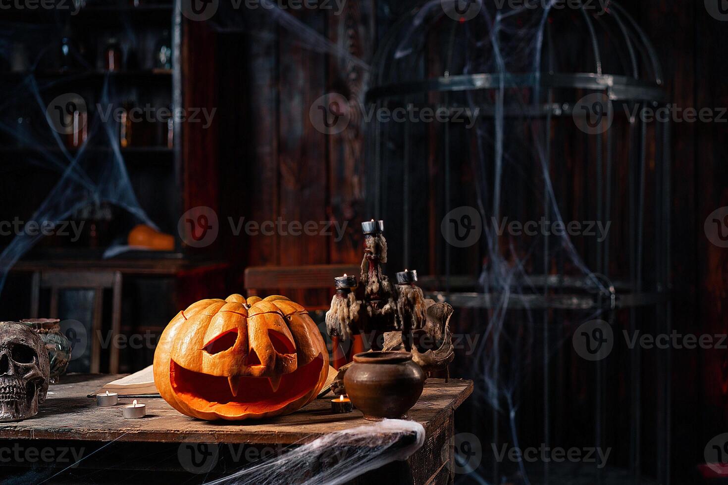 halloween. skrämmande halloween pumpa med ristade ansikte på tabell i mörk rum med ljus, Spindel webb, och bur på bakgrund foto