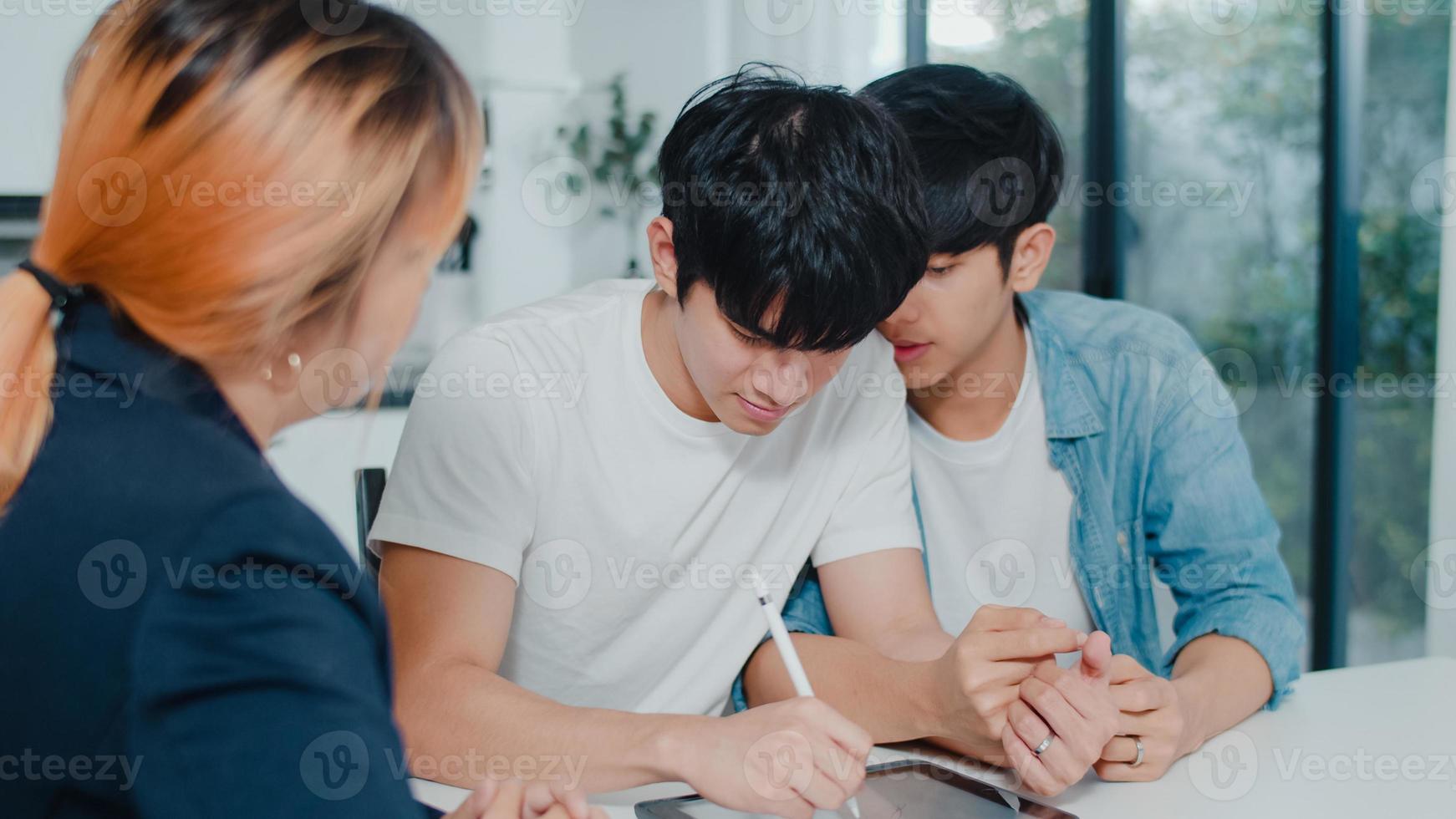 asiatiska gay lgbtq män par underteckna kontrakt på surfplatta hemma, ungt par konsulterar med fastighets finansiell rådgivare, köper nytt hus och handskakning med mäklare i vardagsrummet hemma koncept. foto