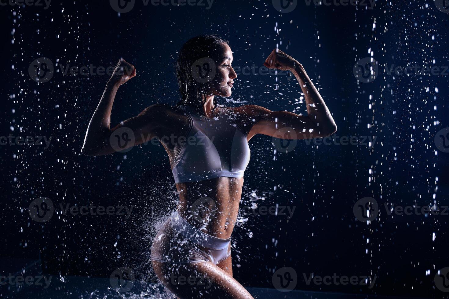 skön atletisk caucasian flicka med en perfekt figur är stående under de vatten. kondition kvinna i en spray av vatten. sporter friskhet foto
