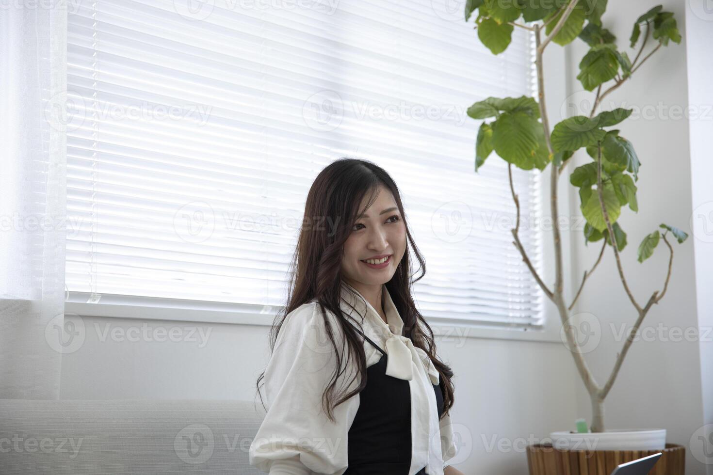 en avslappnad japansk kvinna förbi avlägsen arbete i de Hem kontor foto