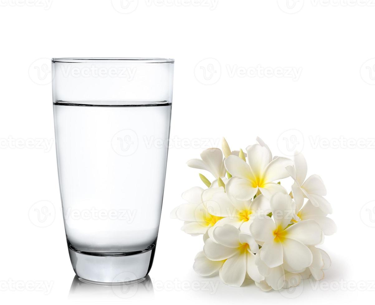 glas vatten och tropiska blommor frangipani foto