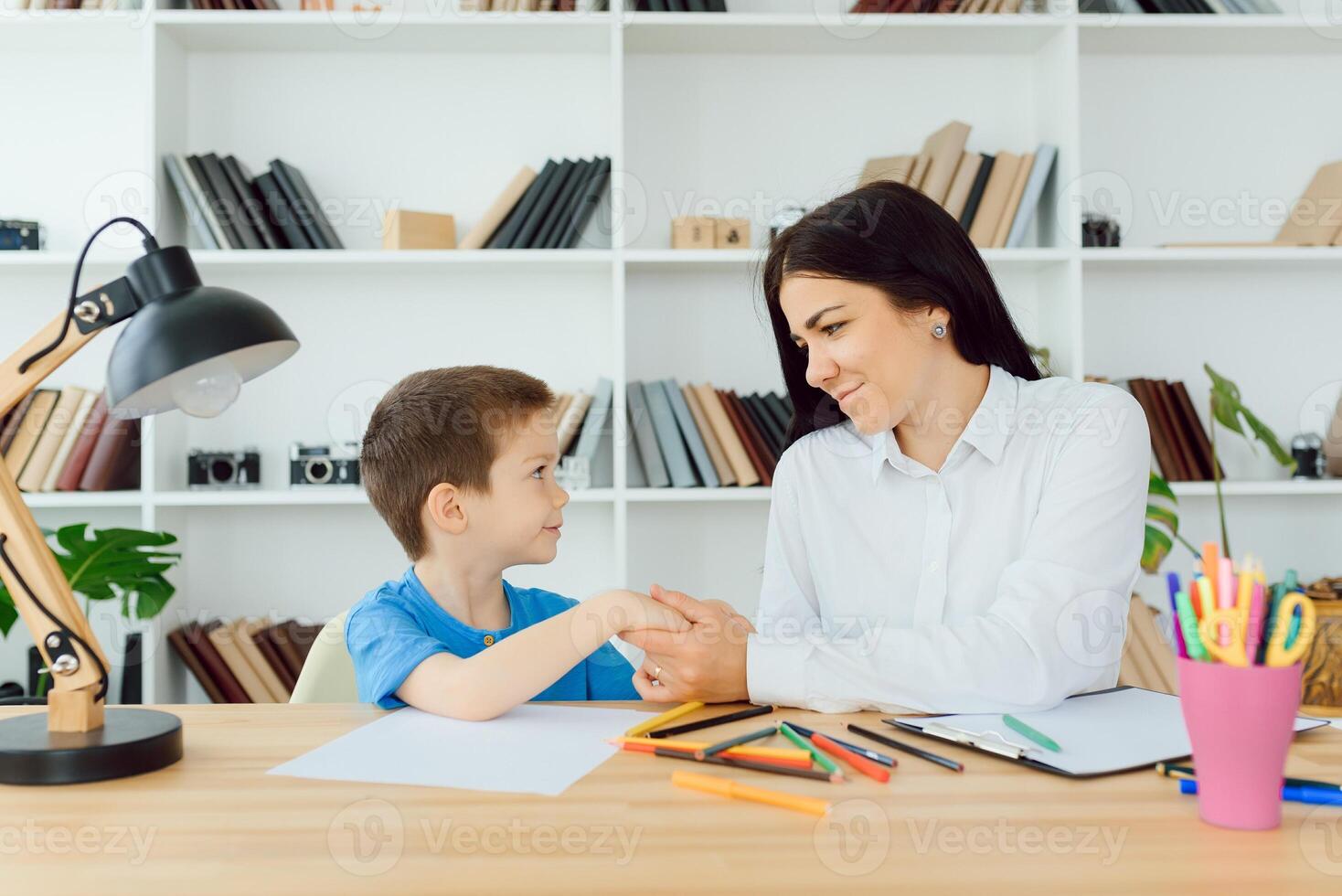 ung kvinna psykolog arbetssätt med liten pojke i kontor foto