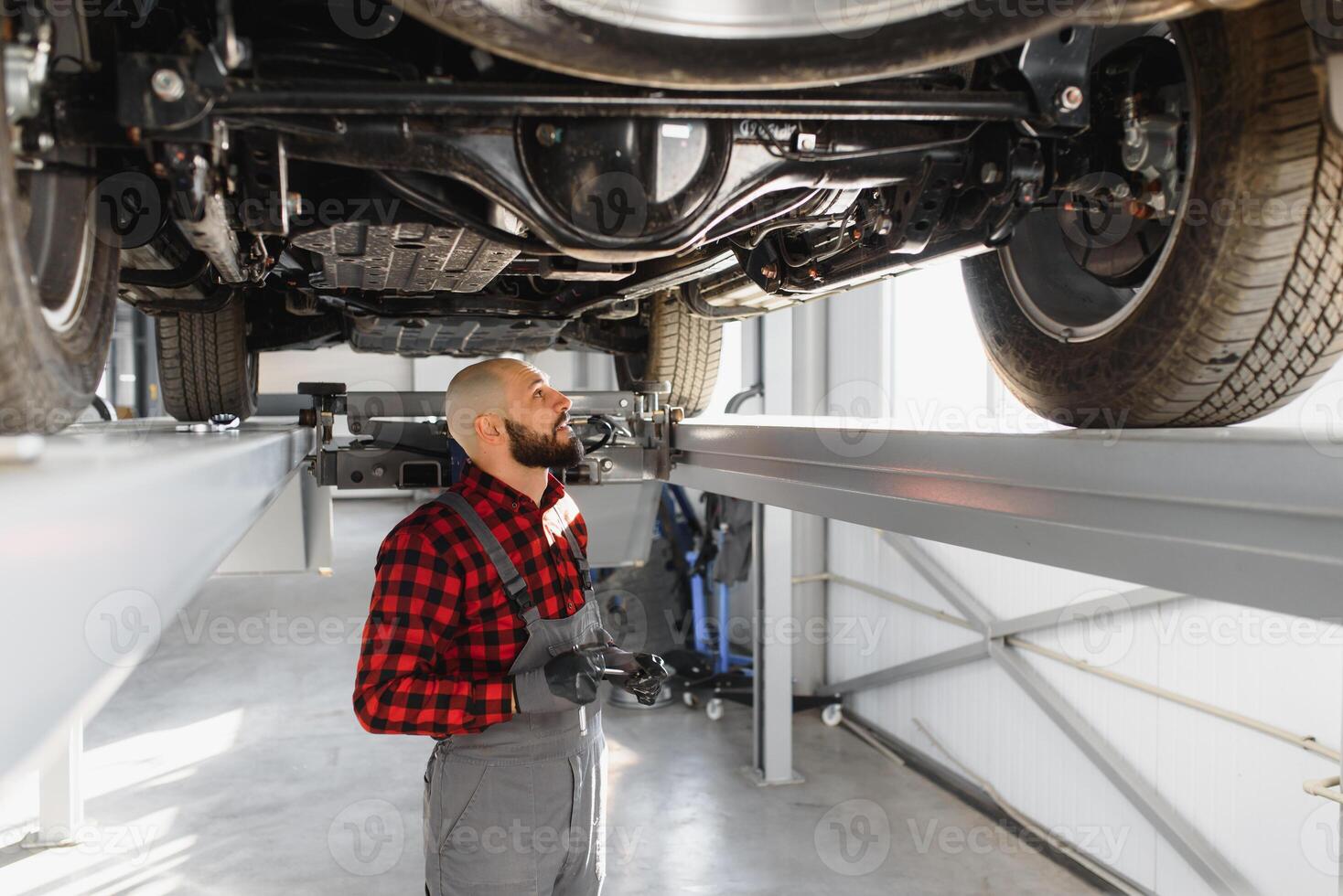 mekaniker arbetssätt under bil på de reparera garage. bil mekaniker arbetssätt i garage. reparera service. foto