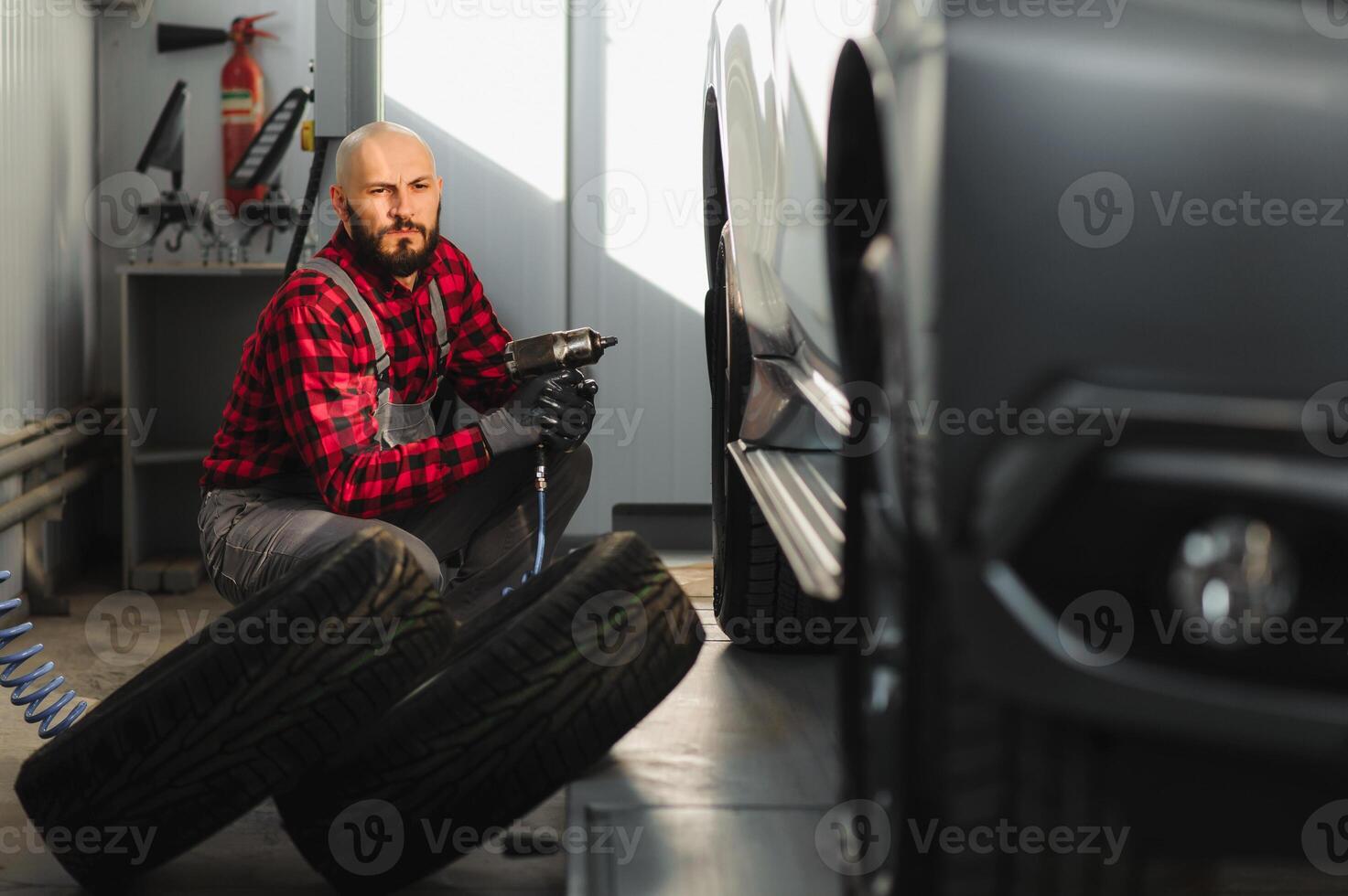 bil mekaniker skruvning eller skruva ur bil hjul av lyft bil förbi pneumatisk rycka på reparera service station foto