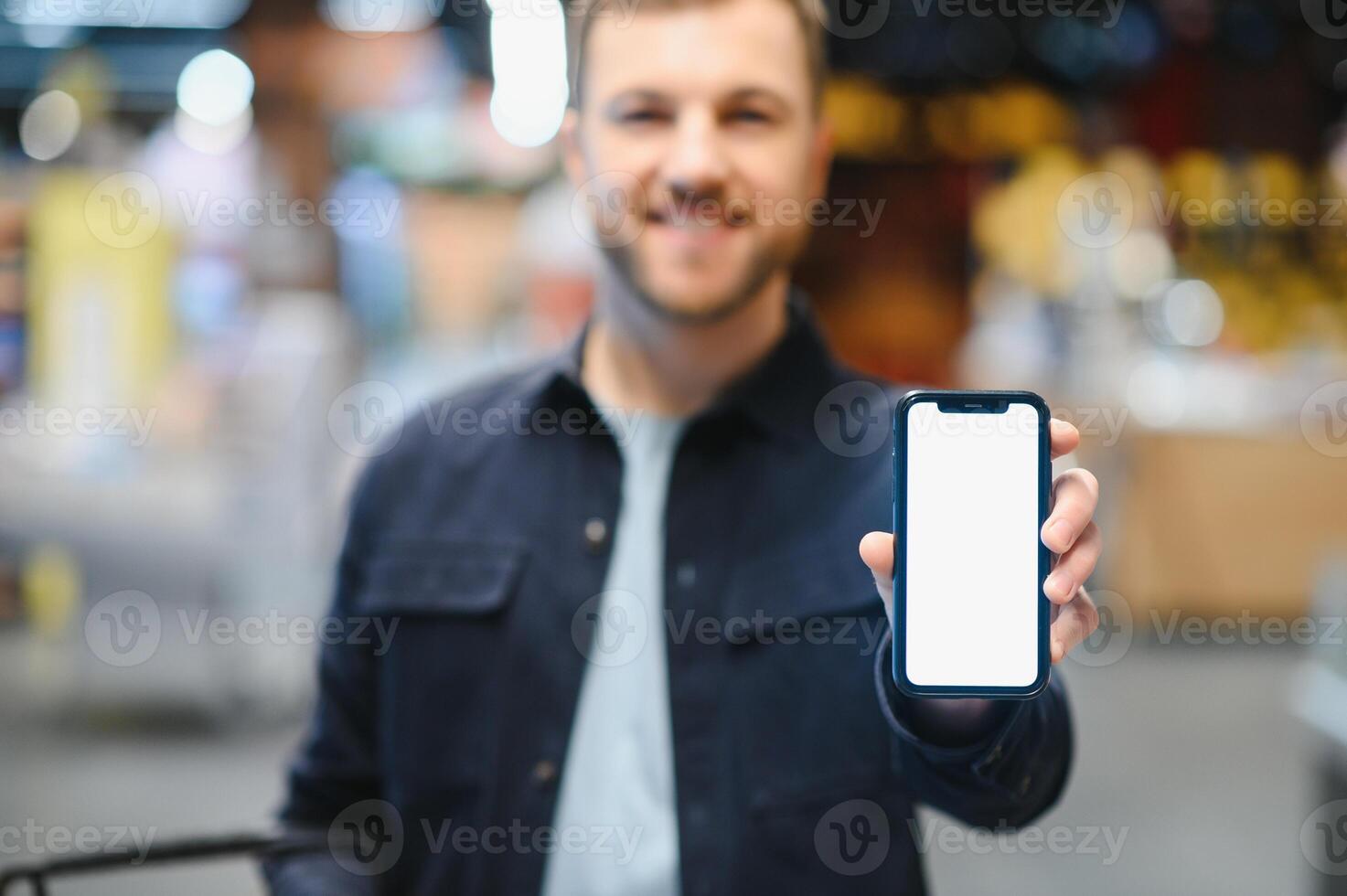 man använder sig av smartphone i mataffär. foto