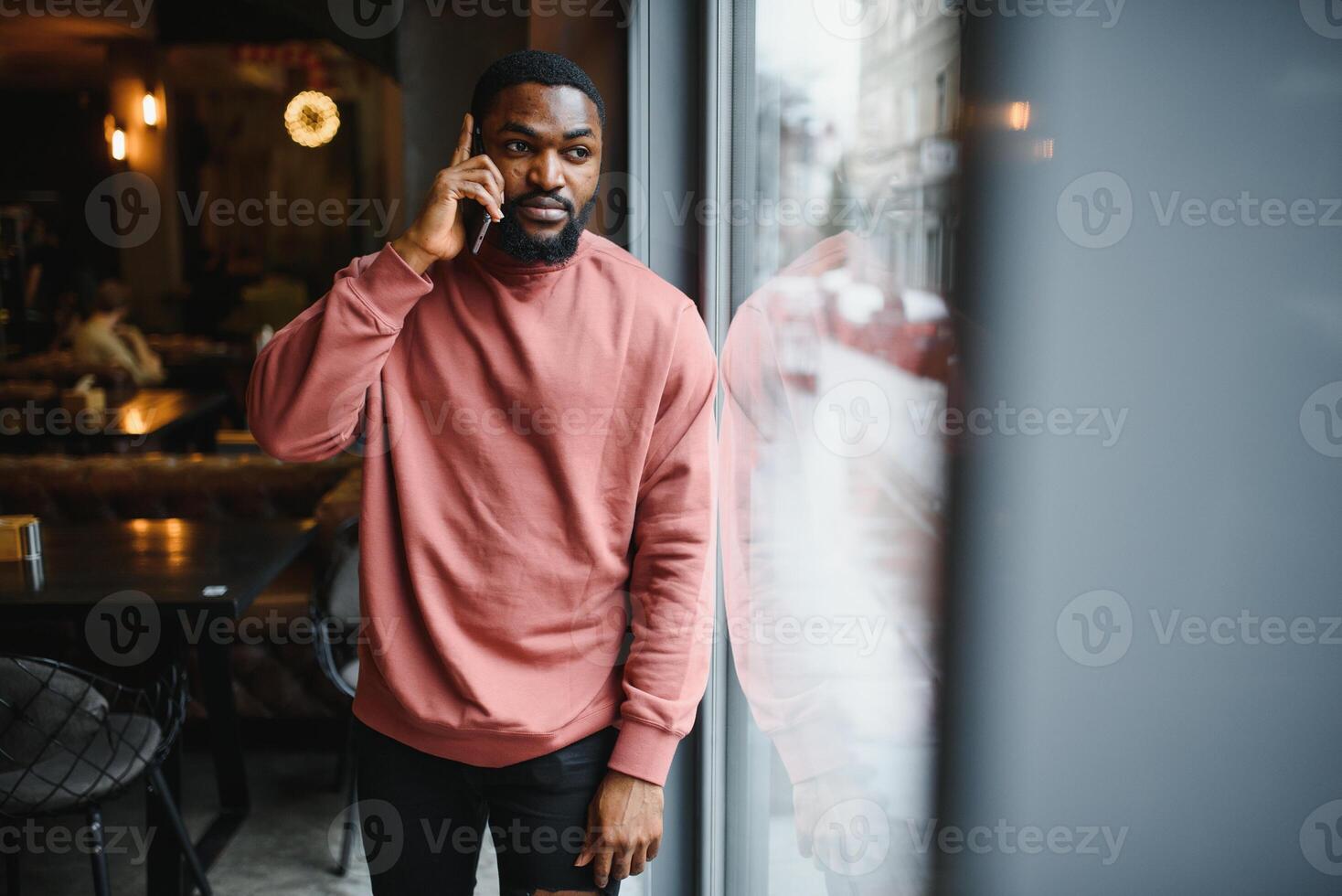 mogna afrikansk amerikan man talande förbi telefon i Kafé. foto