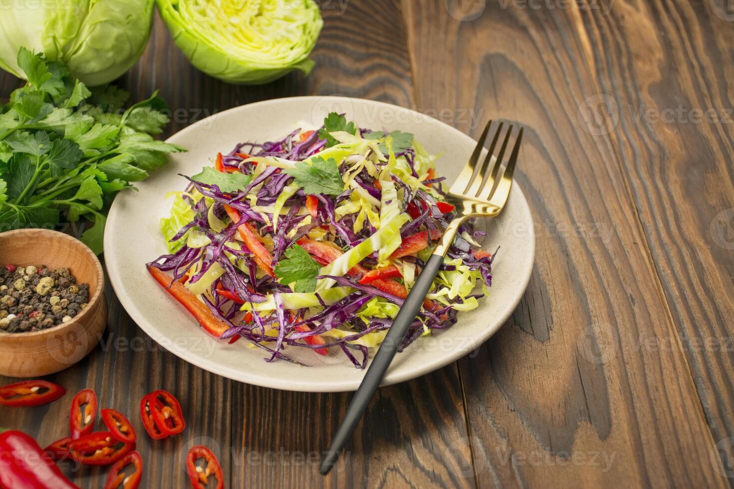 ljus sallad av lila kål, vit kål, klocka peppar i en tallrik på en trä- tabell. färsk vegetabiliska sallad. mat bakgrund. vegetarian maträtt. se från ovan. kopia Plats. foto