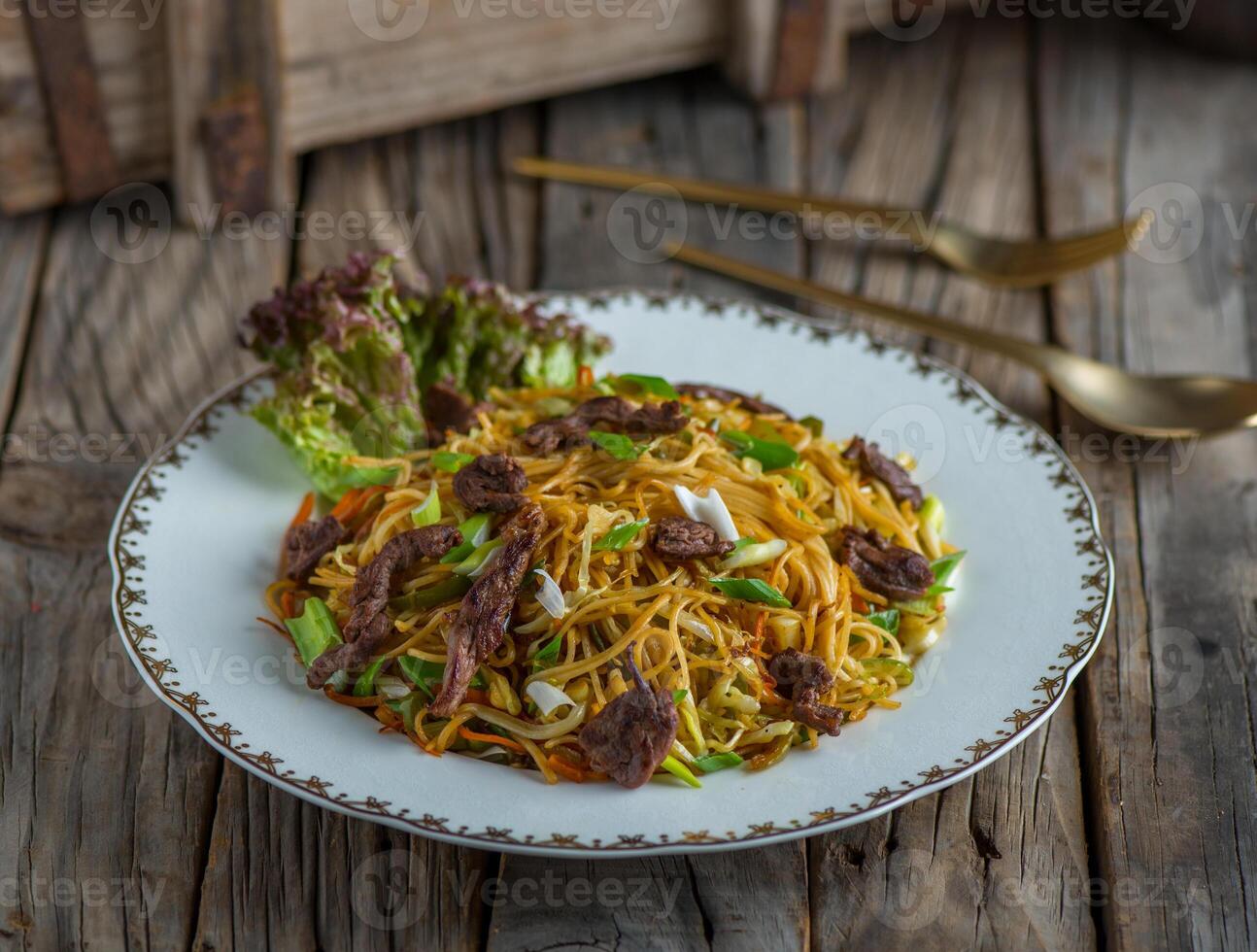 nötkött kinesisk spaghetti eras i en maträtt isolerat på trä- bakgrund sida se av spaghetti foto