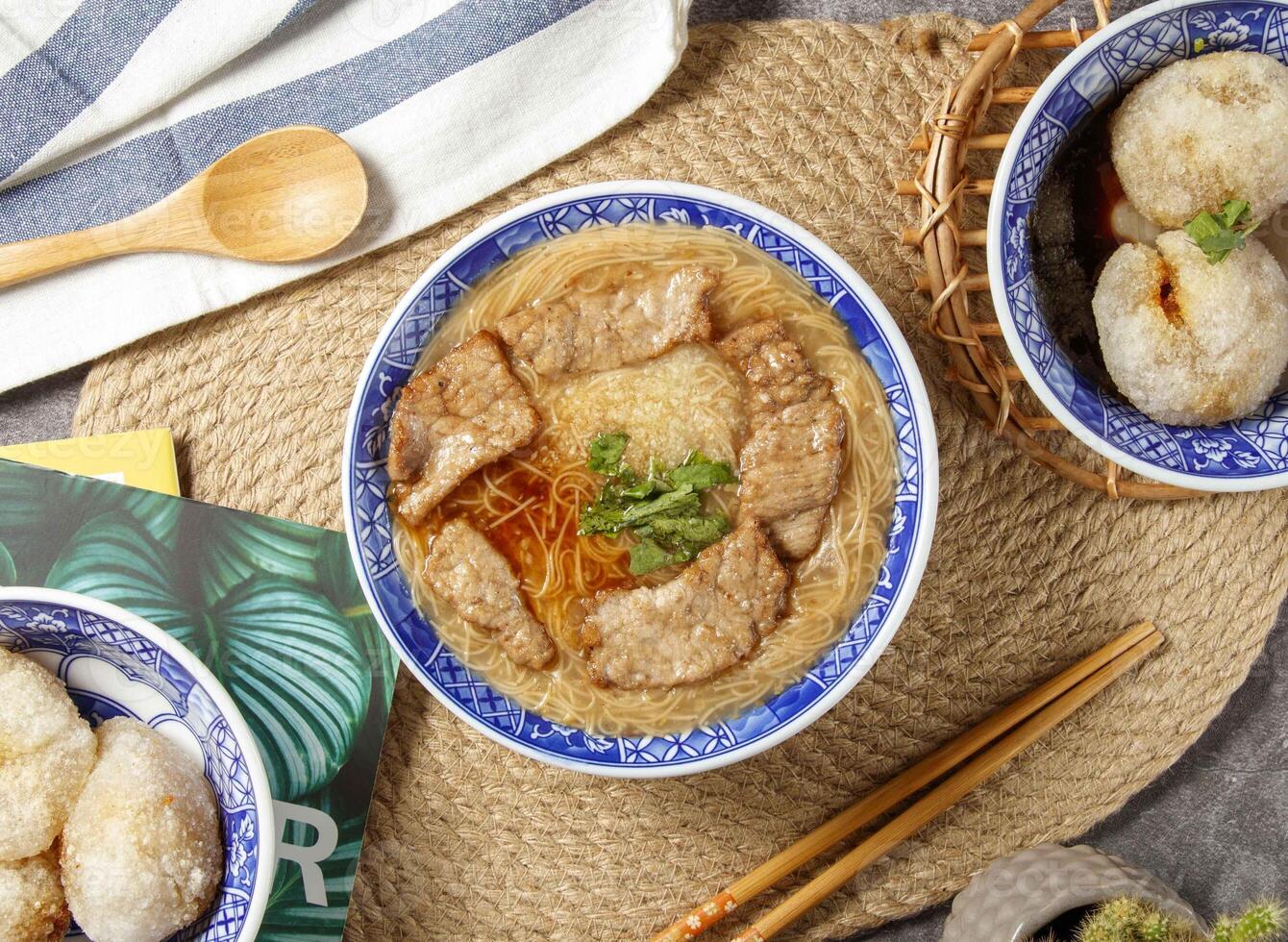 kött soppa spaghetti med ätpinnar och sked eras i skål isolerat på tabell topp se av kinesisk mat foto