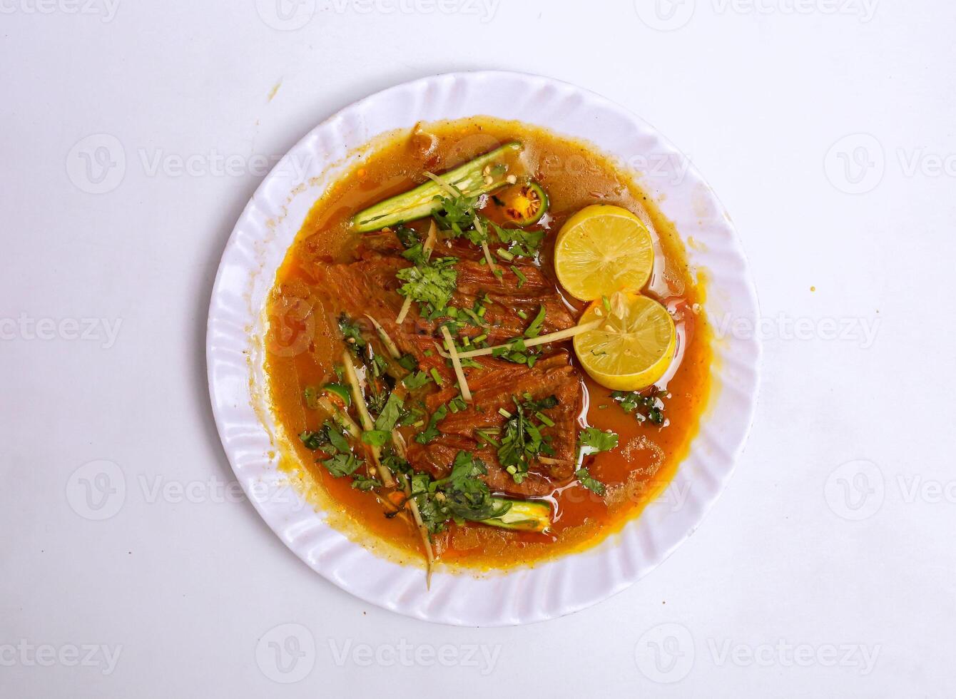 kyckling nihari med citron- skiva eras i tallrik isolerat på grå bakgrund topp se av pakistansk mat foto