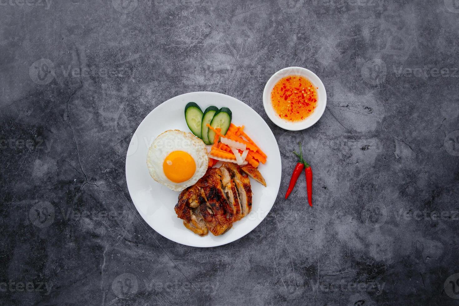 grillad kyckling med ägg, sallad och chili sås eras i maträtt isolerat på mörk grå bakgrund topp se av japansk mat foto