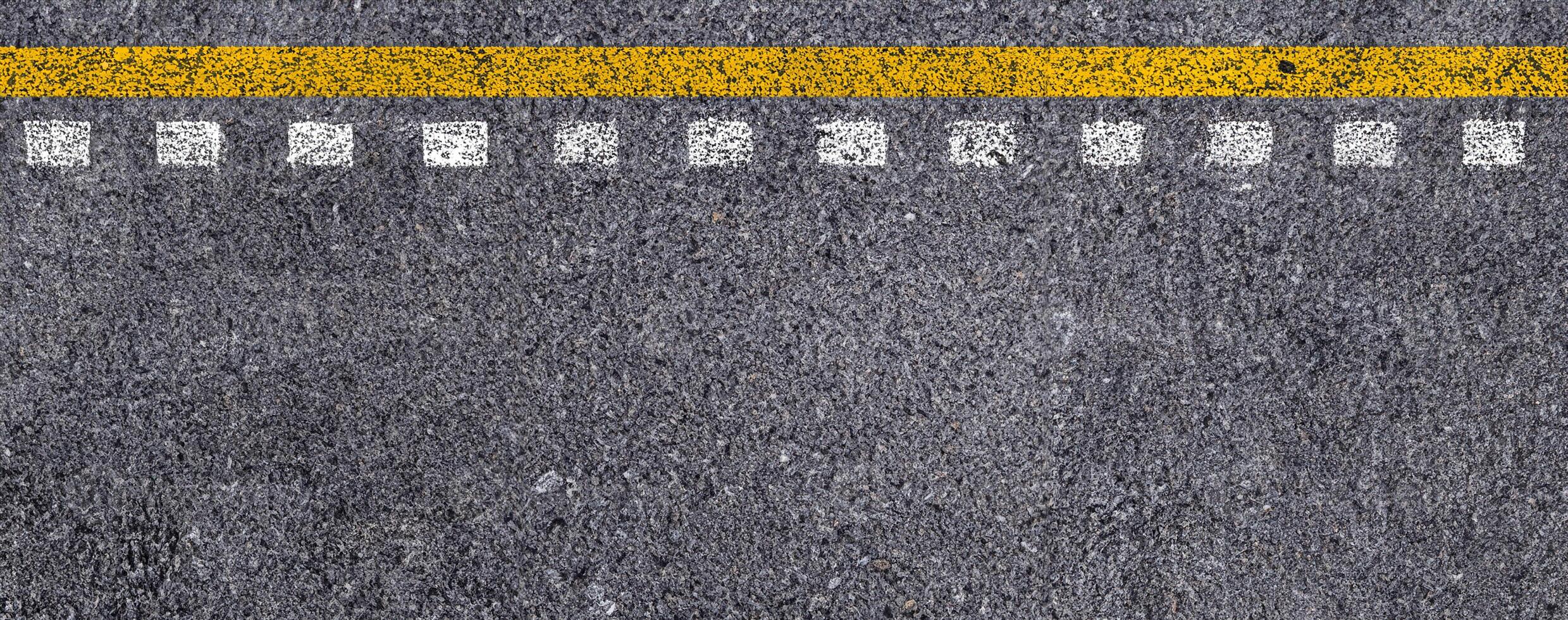 topp se av dubbel- gul och vit rader på asfalt väg textur bakgrund. foto