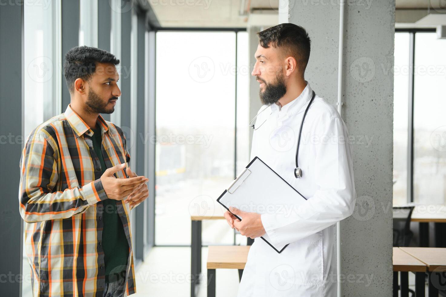 medicin, sjukvård och människor begrepp - Lycklig läkare med Urklipp och ung manlig patient möte på sjukhus foto