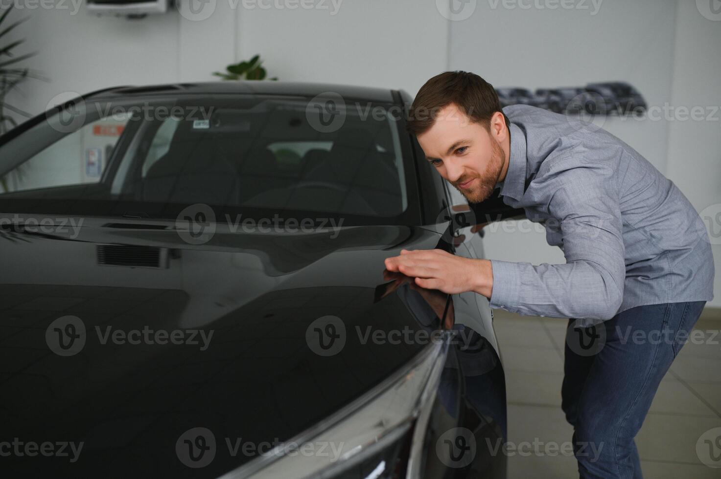 besöker bil återförsäljare. stilig skäggig man är strök hans ny bil och leende foto