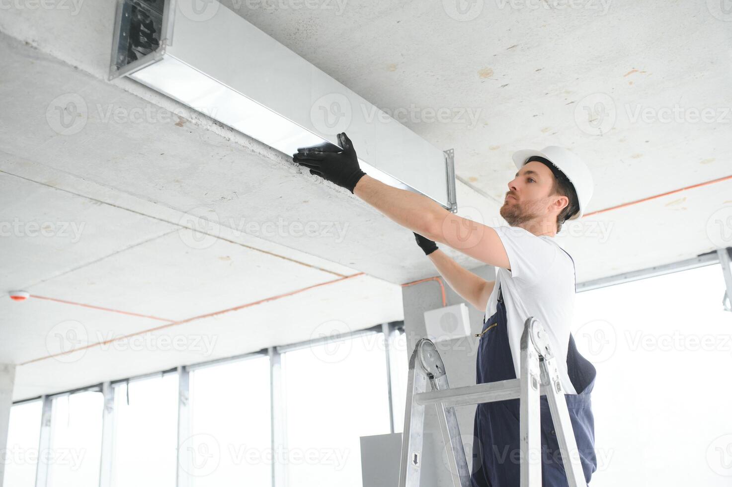 industriell tema. lager uppvärmning och kyl- systemet installation förbi professionell caucasian tekniker. kommersiell byggnad ventilation rektangel kanaler. luft distribution. foto