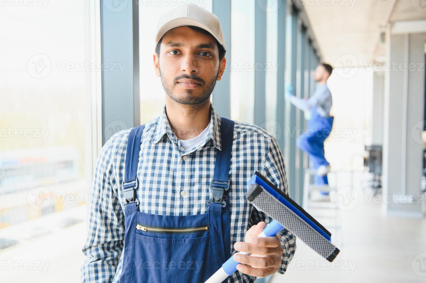 ung indisk man tvättning fönster i kontor foto