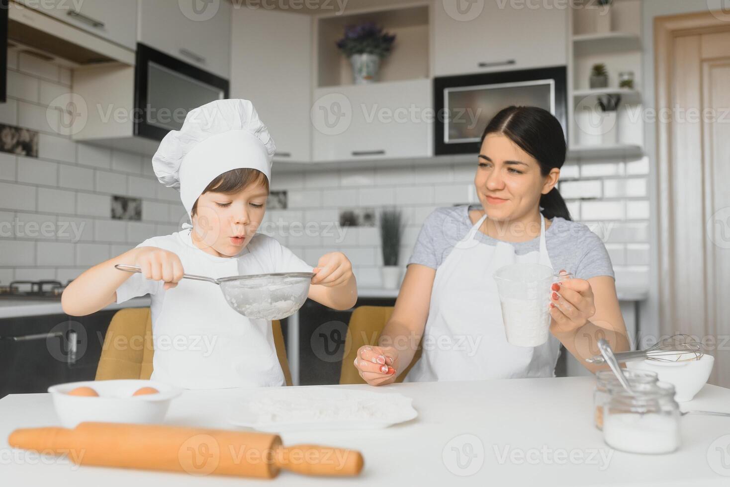 Lycklig familj. mor undervisning henne son på vilket sätt till matlagning kaka meny i morgon. friska livsstil begrepp.. bakning jul kaka och laga mat begrepp foto