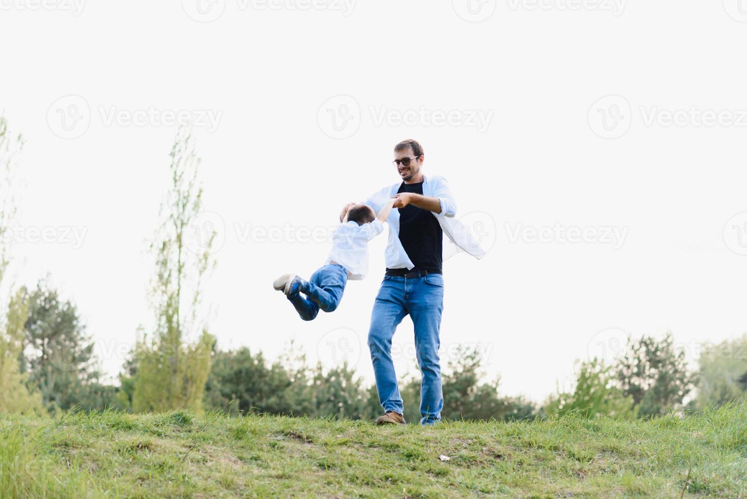 stilig pappa med hans liten söt son är har roligt och spelar på grön gräs- gräsmatta. Lycklig familj begrepp. skönhet natur scen med familj utomhus- livsstil. familj vilar tillsammans. fäder dag foto