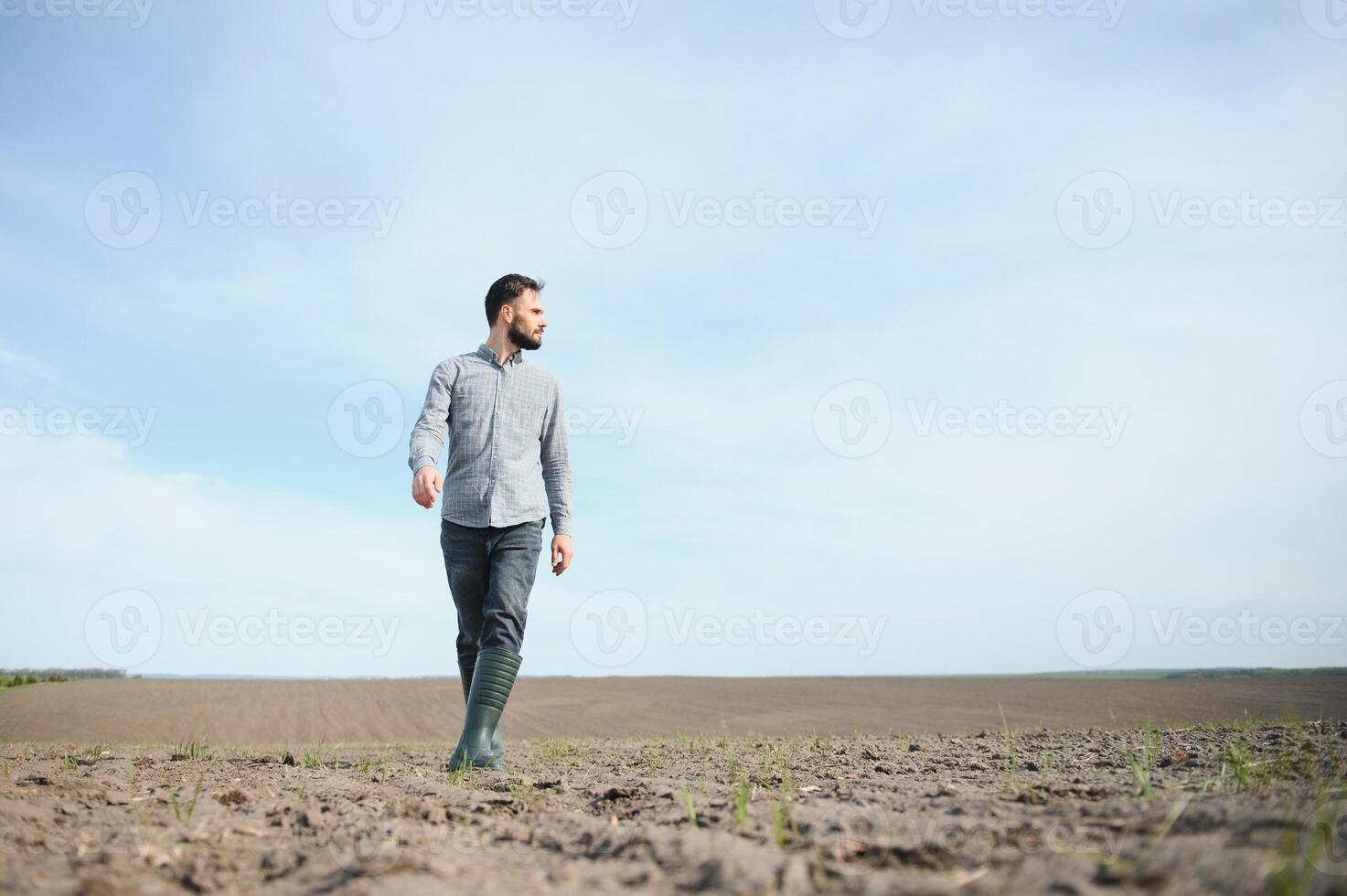 en jordbrukare i stövlar Arbetar i en fält sådd i vår. ett agronom promenader de jorden, bedöma en plogade fält i höst. lantbruk. foto