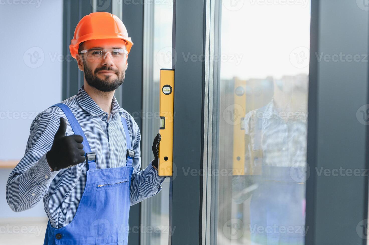 workman i overall montera eller justeras plast fönster i de levande rum på Hem foto