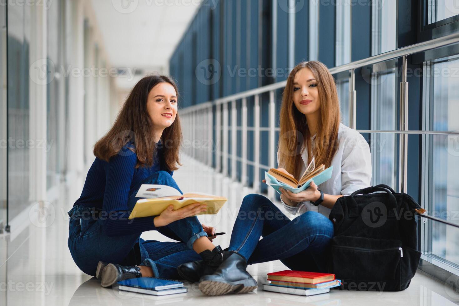 kvinna studenter Sammanträde på de golv och läsning anteckningar innan examen foto