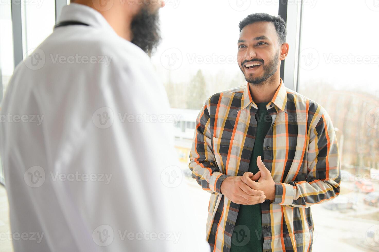 medicin, sjukvård och människor begrepp - Lycklig läkare med Urklipp och ung manlig patient möte på sjukhus foto