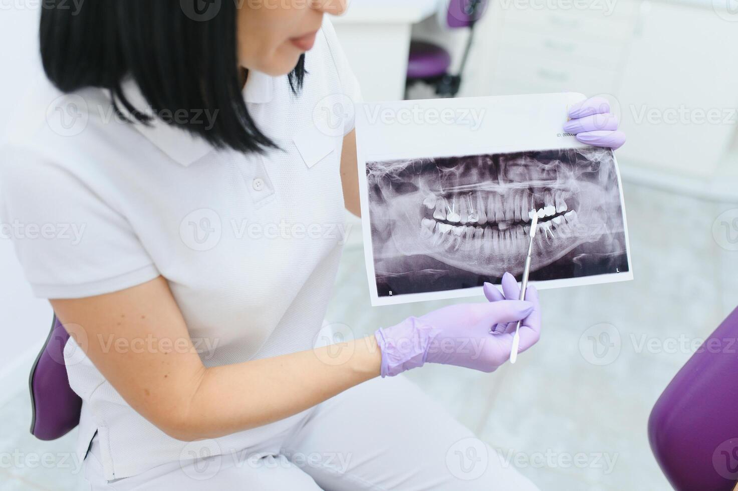 tandläkare förklara de detaljer av en röntgen tänder bild till hans patient i klinik. oral vård, ortodonti. foto