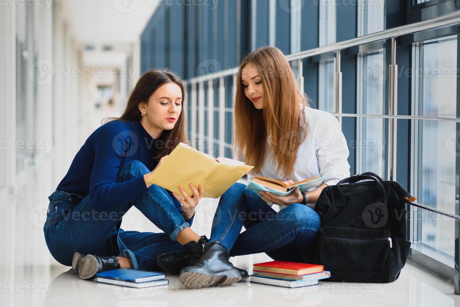 kvinna studenter Sammanträde på de golv och läsning anteckningar innan examen foto