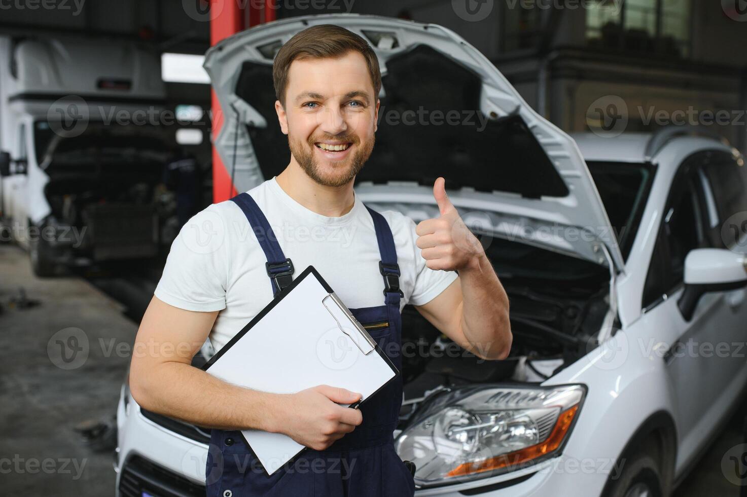 bil service, reparera, underhåll och människor begrepp - Lycklig leende bil mekaniker man eller smed med Urklipp på verkstad foto