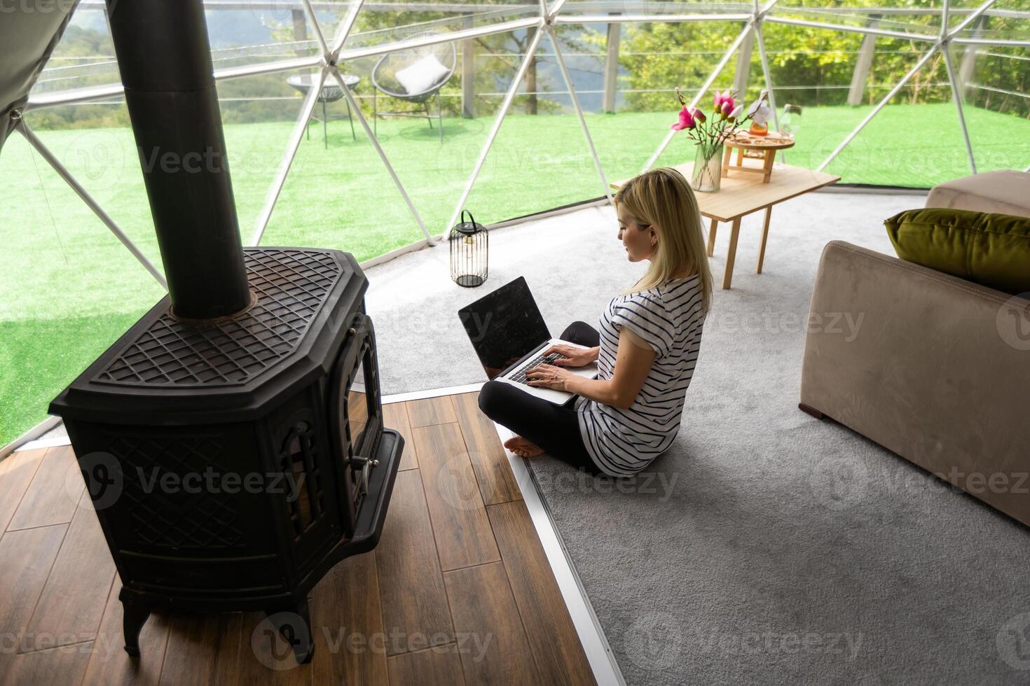 mitten åldrig kvinna användningar en bärbar dator vilar och utgifterna tid på glamping hus på högtider. Semester kupol tält. mysigt, camping, hygge, livsstil begrepp foto