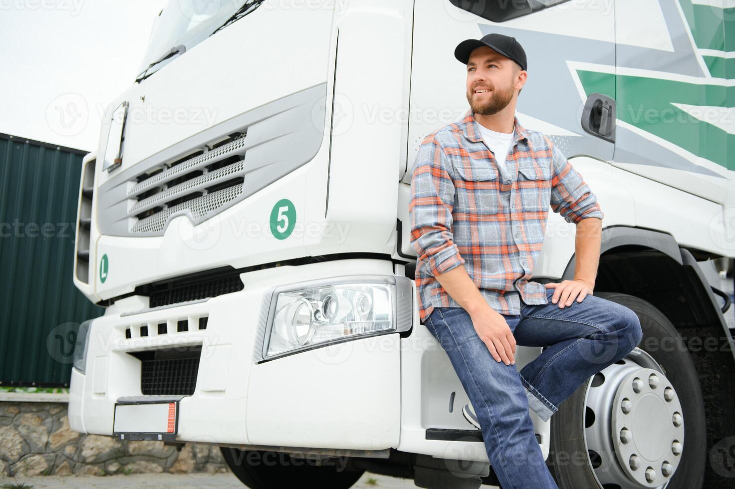stolt professionell trucker stående i främre av hans lastbil. lastbilstransporter och transport tema. foto