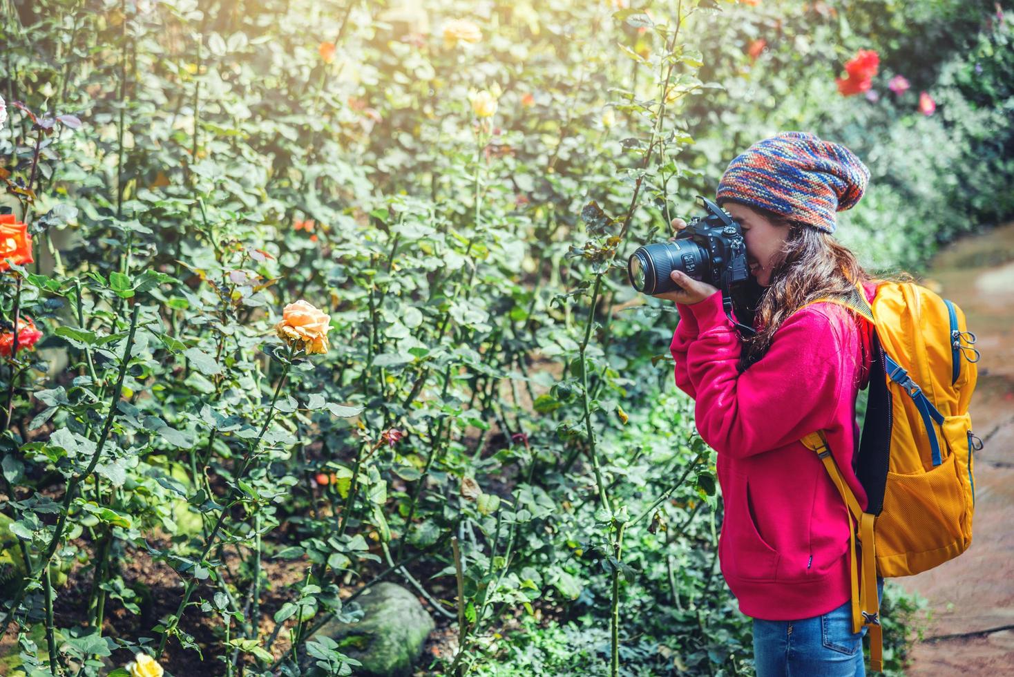 flickan som står och håller i kameran och fotograferar rosor i trädgården. foto