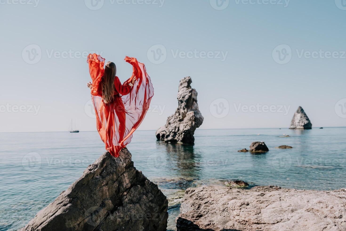 kvinna resa hav. ung Lycklig kvinna i en lång röd klänning Framställ på en strand nära de hav på bakgrund av vulkanisk stenar, tycka om i Island, delning resa äventyr resa foto