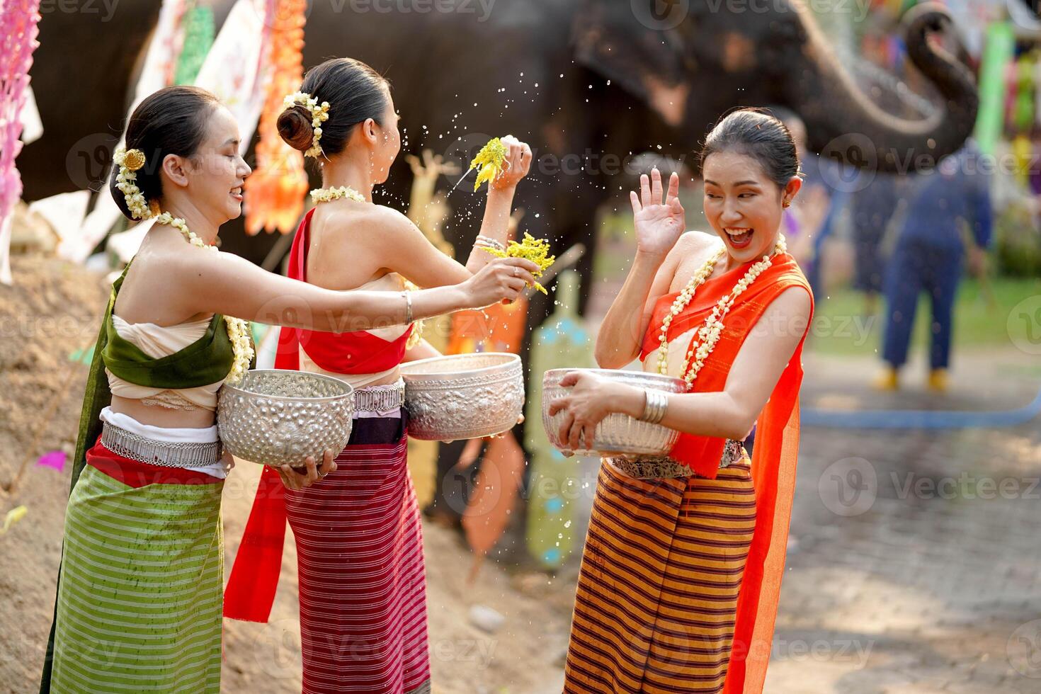 grupp av thai kvinnor gods thai traditionell klänning spela till stänk vatten på de thai ny år dag eller songkran festival i en roligt sätt på elefant och lugg av sand bakgrund. foto