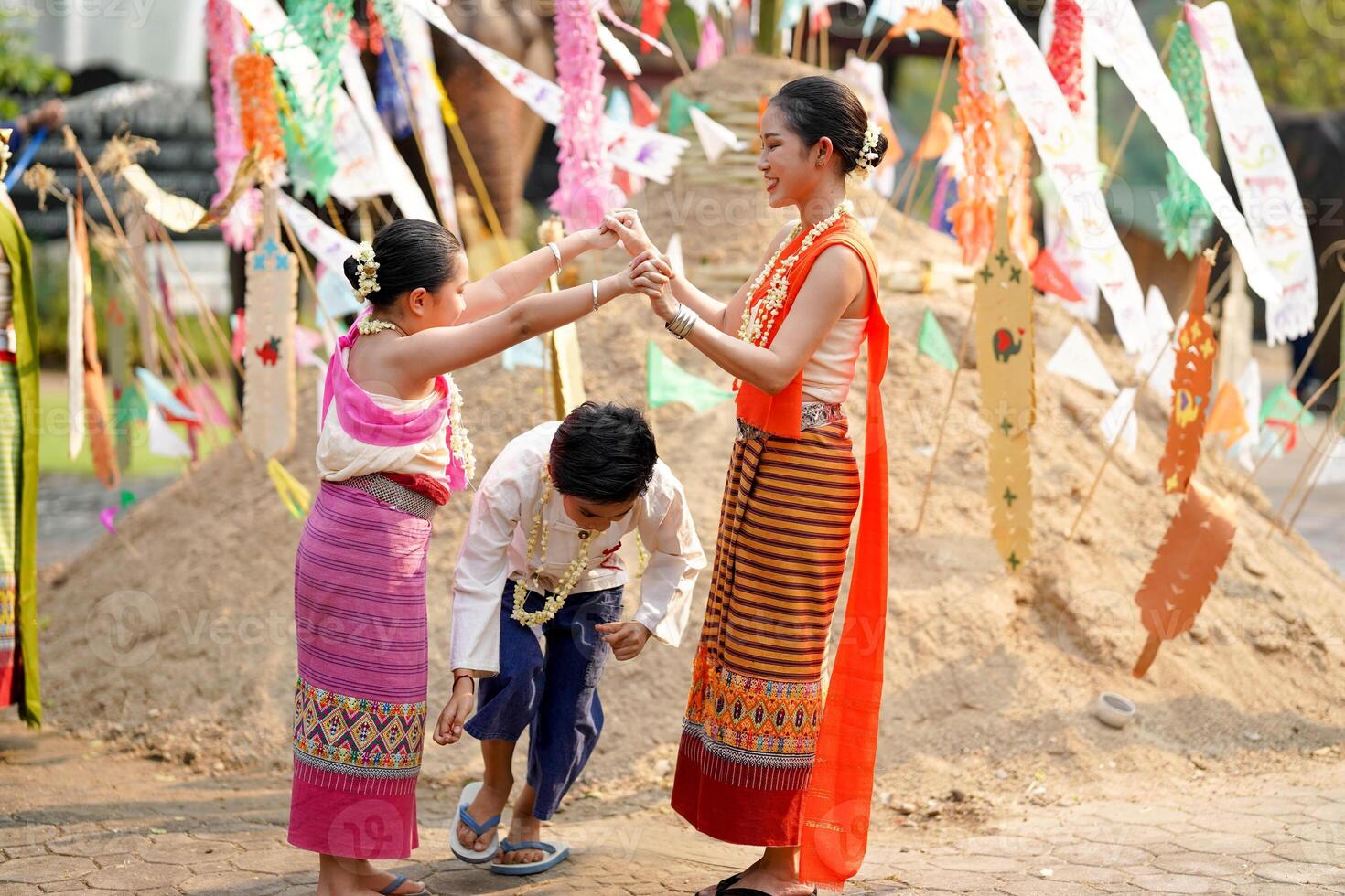 skön thai ung kvinnor och flicka och gods thai traditionell klänning spelar mänsklig grotta tåg med en pojke på lugg av sand i tempel på de songkran festival. foto