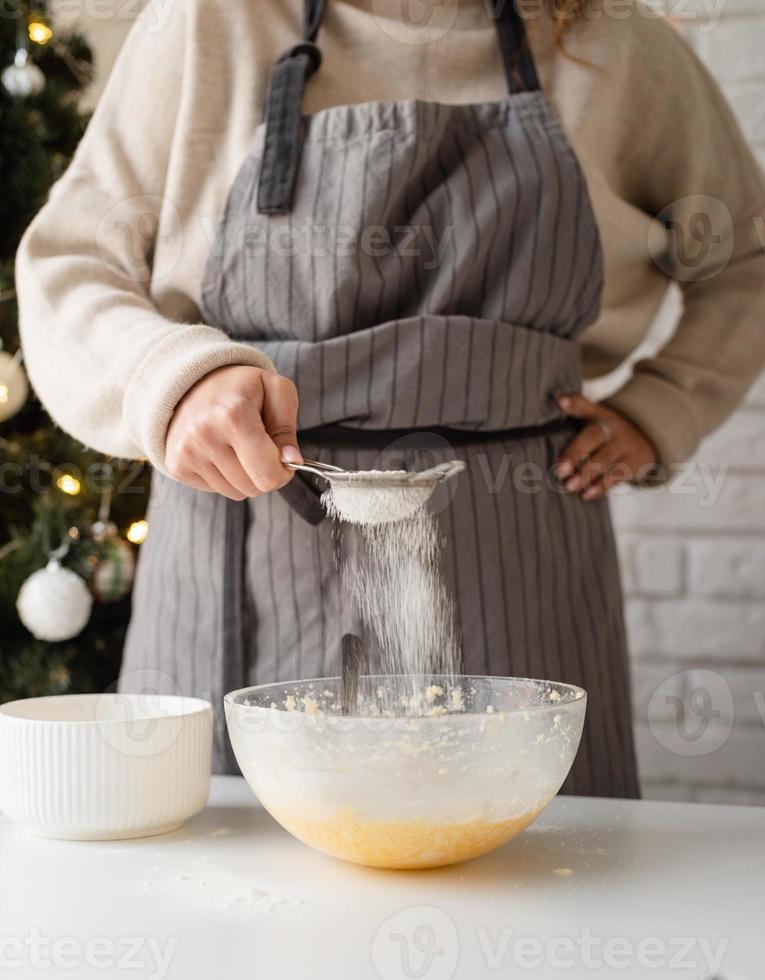 leende kvinna i köket baka julkakor foto