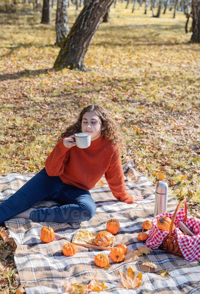 vacker kvinna i röd tröja på en picknick i en höstskog foto