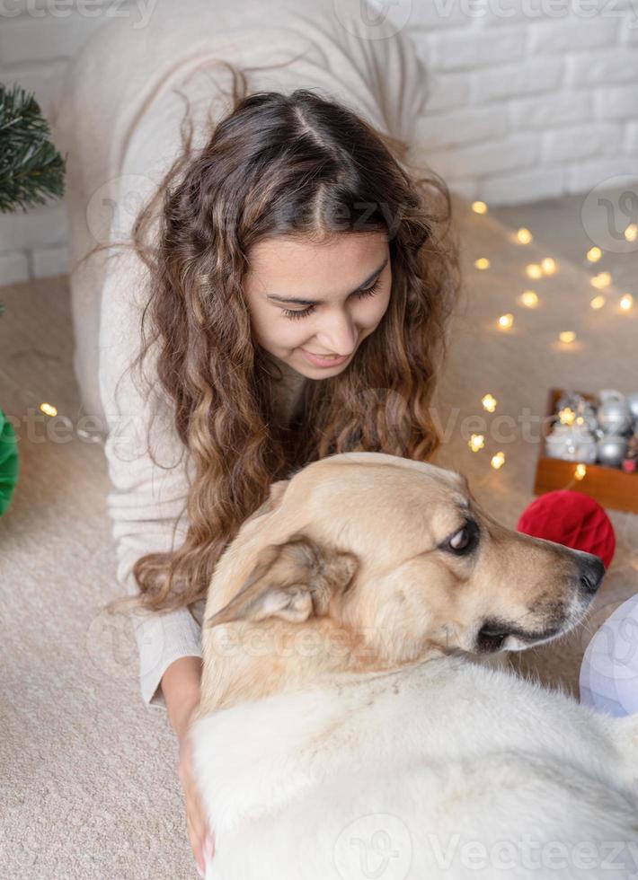 ung attraktiv kvinna dekorerar julgranen och leker med hundar foto