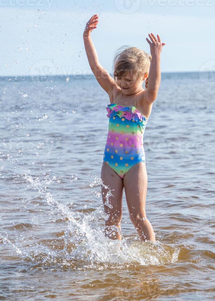 ung Lycklig barn flicka av europeisk utseende ålder av 6 har roligt i vatten på de strand och stänk, tropiskt sommar yrken, helgdagar.a barn åtnjuter de hav.vertikal photo.copy Plats. foto