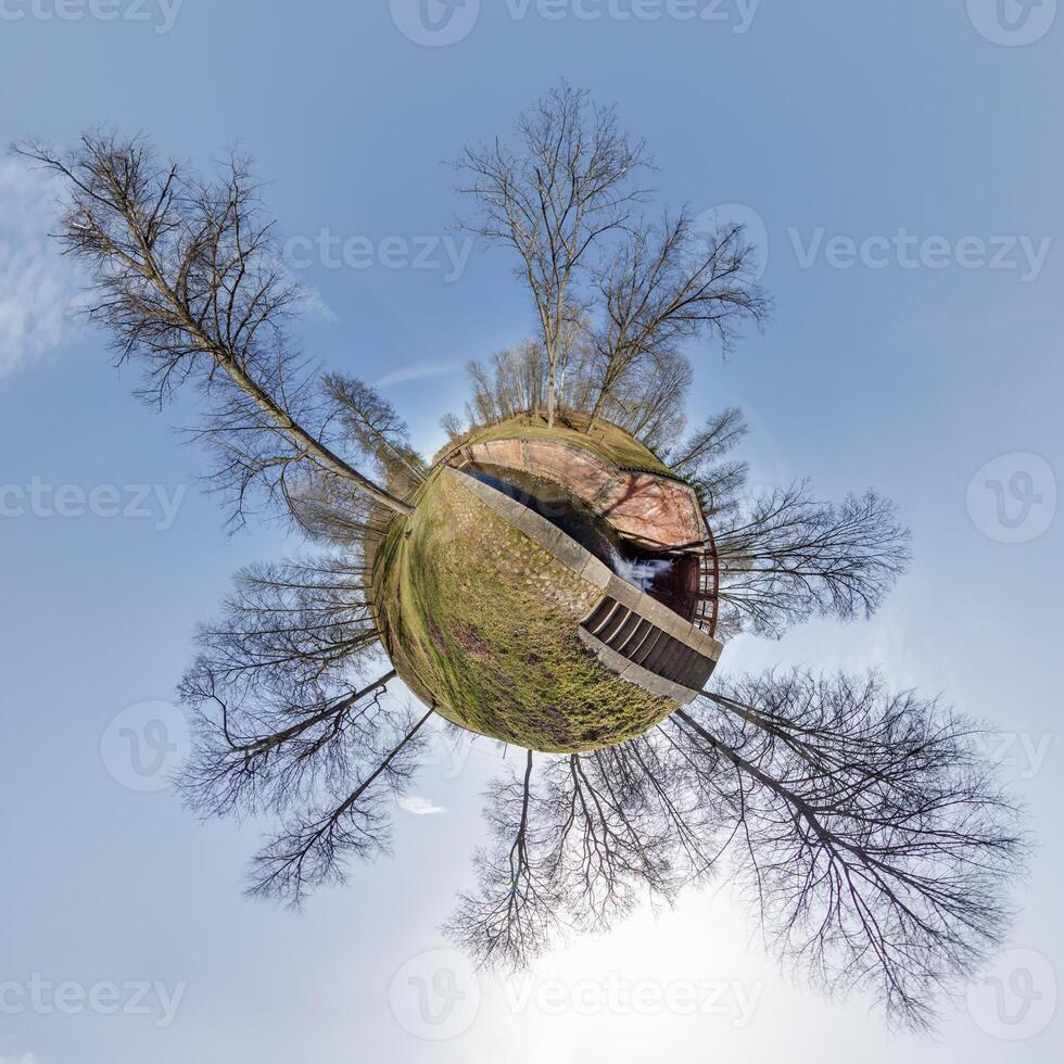 mycket liten planet omvandling av sfärisk panorama 360 grader. sfärisk abstrakt antenn se med träd i skog med klumpig grenar i blå himmel. krökning av Plats. foto