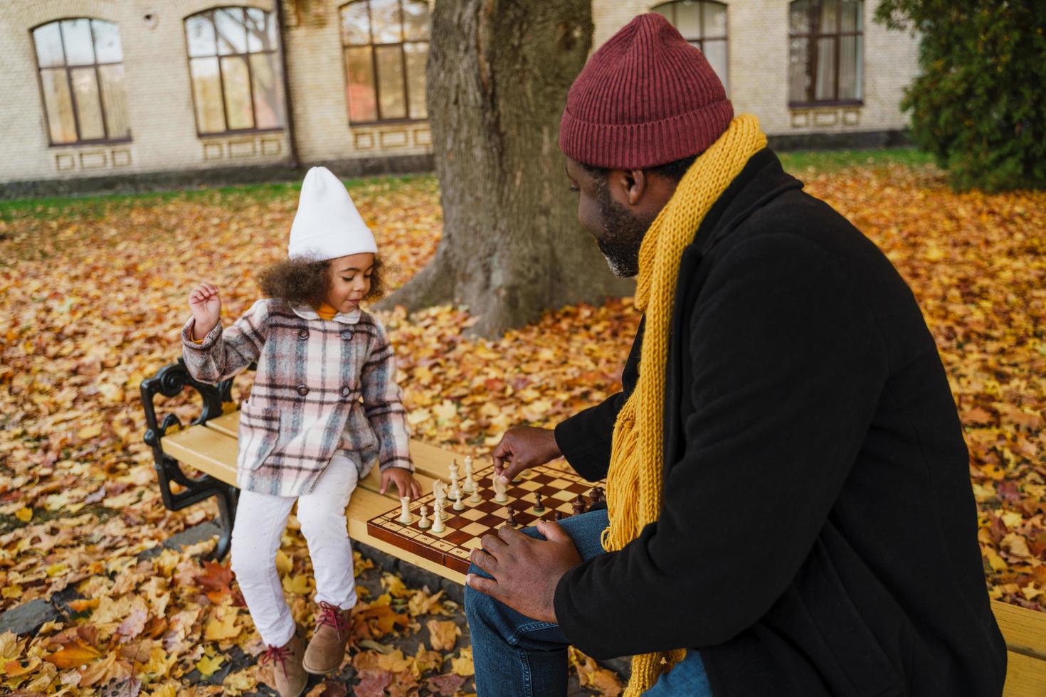 svart farfar och barnbarn spelar schack i höst park foto