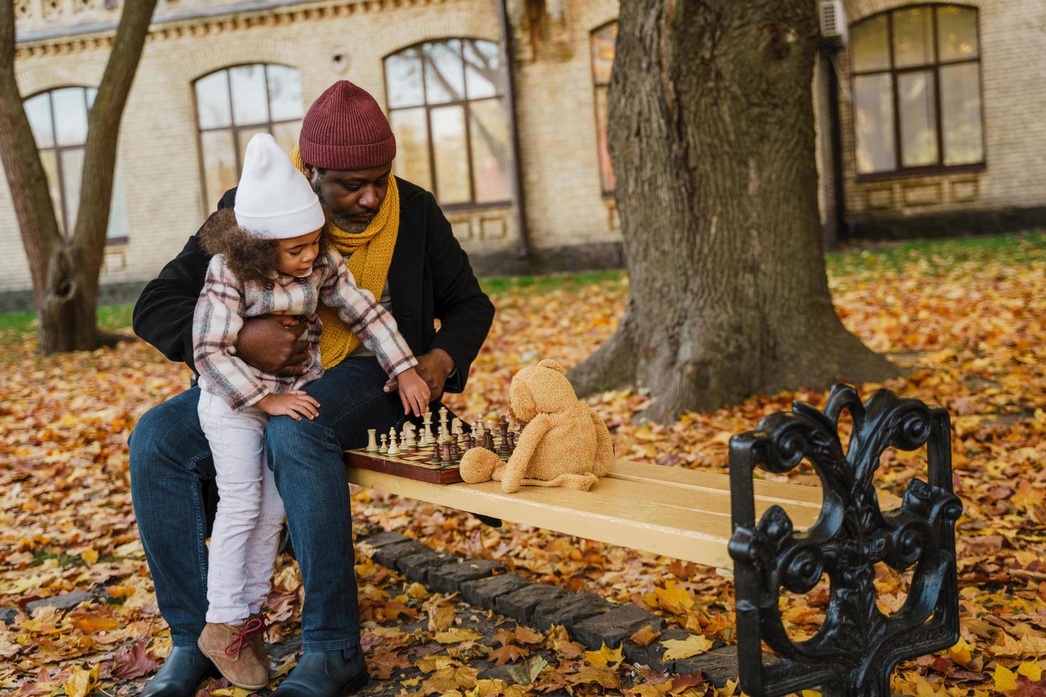 svart farfar och barnbarn spelar schack i höst park foto