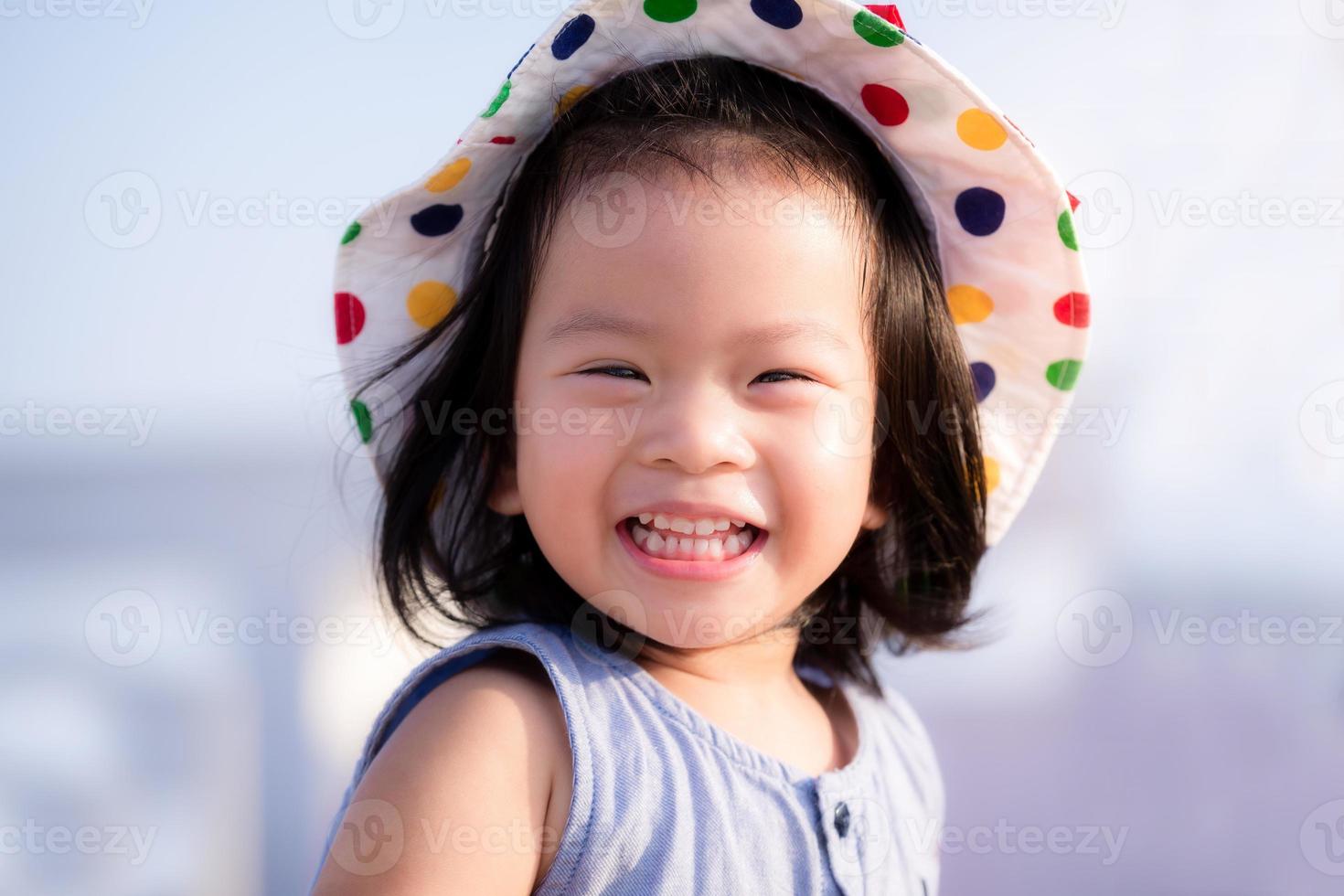 asiatisk baby barn flicka strålande leende. närbild glada ansikte. liten flicka som bär vit hatt. halvkroppsfoto. hon har karies. bebis ålder 2 år och 9 månader gammal. foto