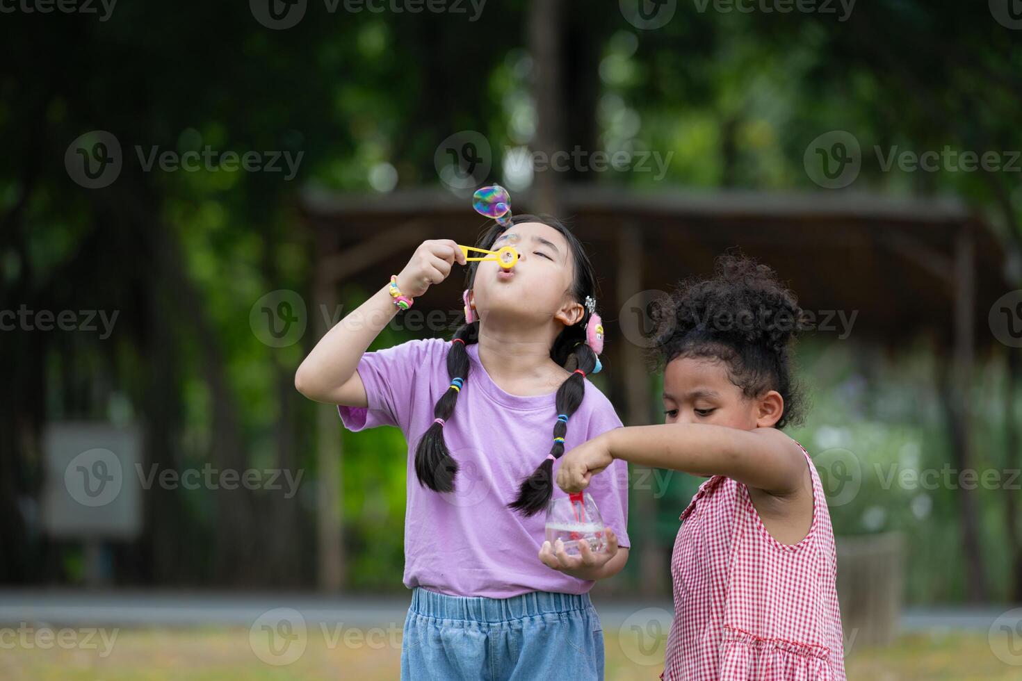 flickor i de parkera med blåser luft bubbla, omgiven förbi grönska och natur foto