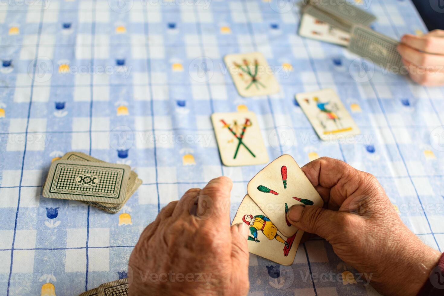 äldre händer spelar kort på en blå tabell foto