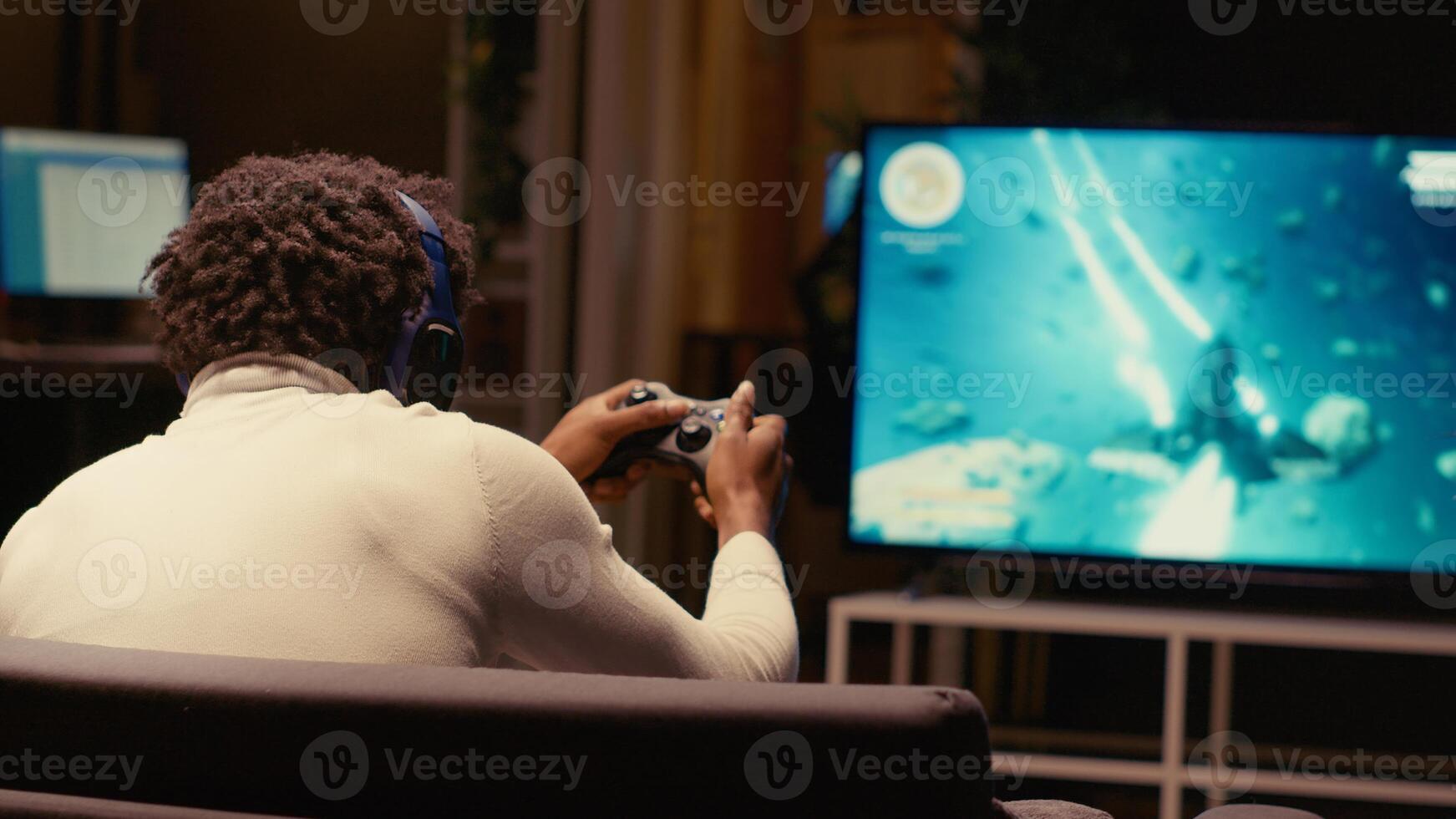 afrikansk amerikan gamer upphetsad efter vinnande spel spelar arkad Plats skytten på ultrawide tv. man utgifterna tid i lägenhet på gaming systemet, Lycklig till till sist lösa enspelarläge TV-spel uppdrag foto