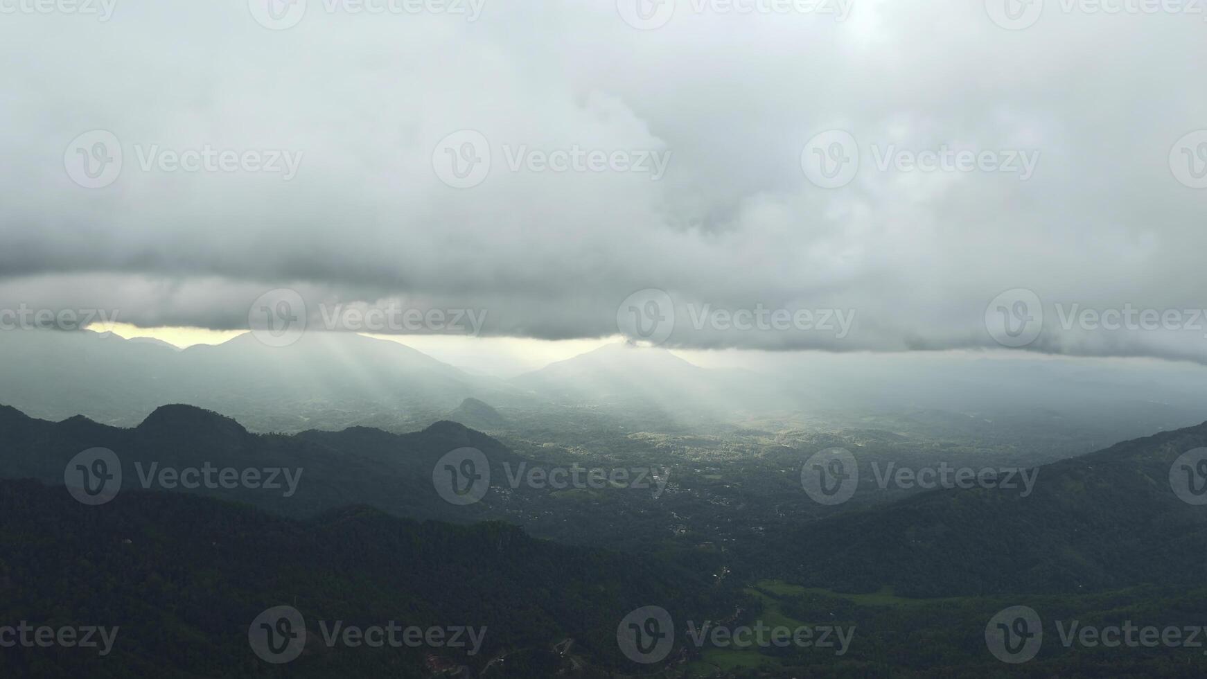 skön se av berg grön dal med moln och solljus. handling. pittoresk landskap av grön bergen och låg moln med Sol brytning genom. solens strålar på horisont i grön berg foto